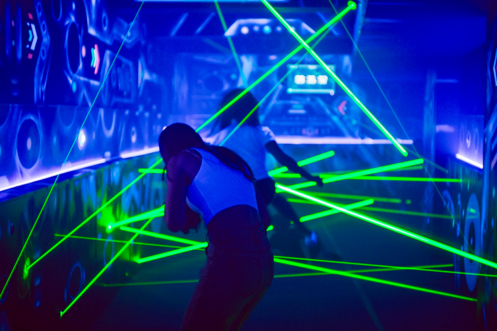 Two ladies running with green lasers in the premises of the Laser Labyrinth in Brno