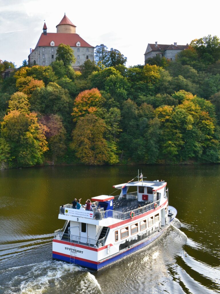 view of a boat traveling along the Brno dam below the Veveří castle