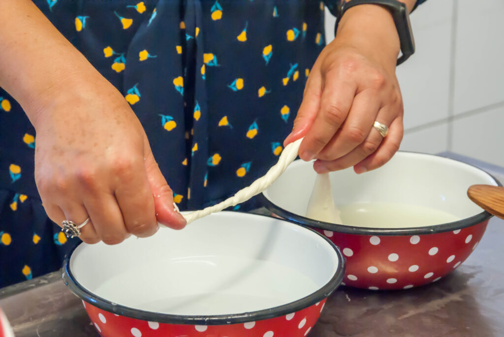 Making a korbáčik above two red bowls with polka dots