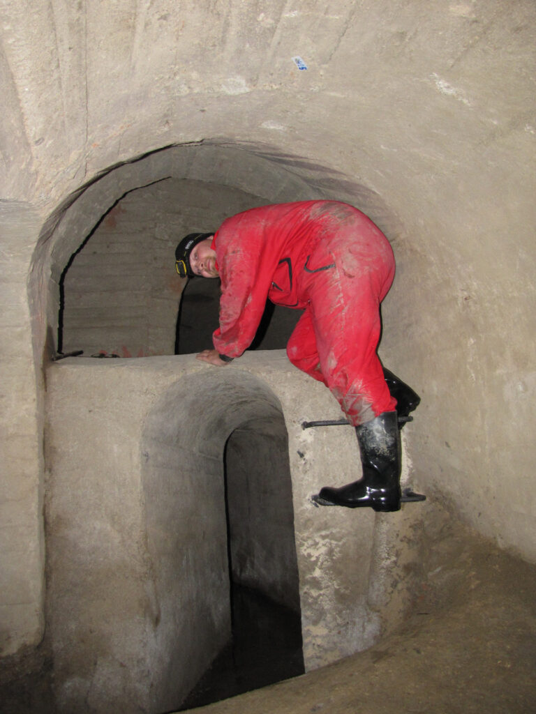 A man in a red overall crawling in the Znojmo underground