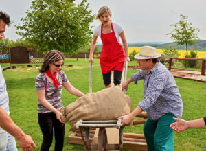 team building activity where a lady pushes a wheelbarrow with a bag of flour at the Bukovany mill