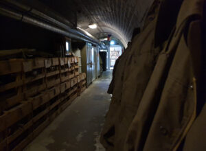 Bunker 10-z area with hanging coats on one side and stacked crates on the other