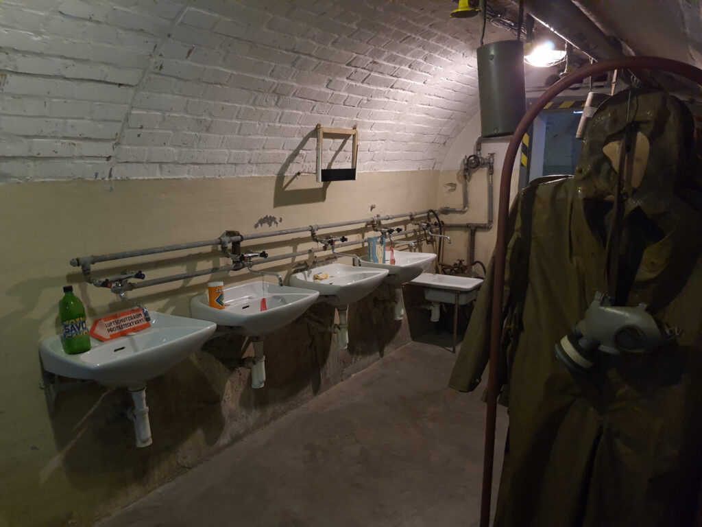 Bunker 10-z area with sinks on one side and gas masks and coats on the other